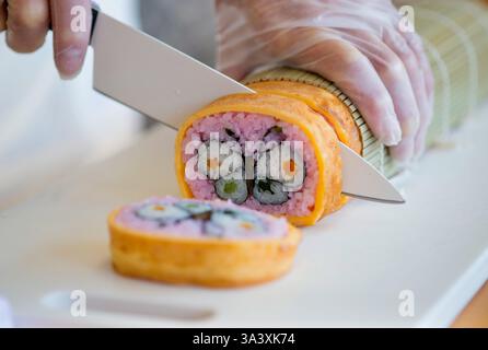 Tomie Hirano taglia un futomaki matsuri sushi (spessi rotoli festivi) per rivelare un design a farfalla all'Hanamiyui, una scuola di cucina a Kamogawa, C. Foto Stock