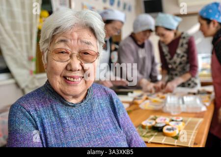 Eiko Ryuzaki posa per una foto come alcune delle sue accuse fanno il sushi futomaki matsuri (rotoli spessi per le feste) a Hanamiyui, una scuola di cucina a Kamogawa, Foto Stock