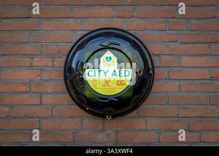 AED urbano montato su un muro in mattoni di pietra. Un defibrillatore semiautomatico esterno, o defibrillatore semiautomatico esterno, viene utilizzato per aiutare coloro che hanno subito un arresto cardiaco improvviso. Foto Stock