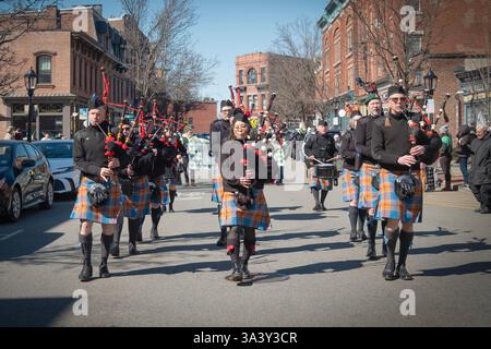 La cornamusa e la drum band degli Hudson Highlanders nelle loro colorate gonne tartan si esibiscono alla Beacon's St. Patrick's Day Parade of Green a Beacon, New York Foto Stock