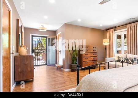 Camera accogliente con comodo letto, comò elegante, divano invitante e ventilatore a soffitto per un flusso d'aria ottimale Foto Stock