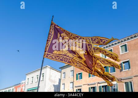 La bandiera del Veneto con il Leone alato di San Marco che sventolava al vento nel centro di Chioggia, Italia Foto Stock