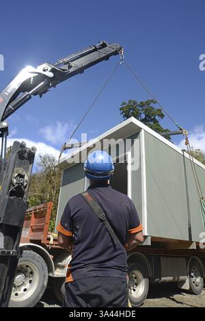 GREYMOUTH, NUOVA ZELANDA, 21 OTTOBRE 2020: Un operatore di gru lavora per sollevare un piccolo edificio da un camion sui suoi pali Foto Stock
