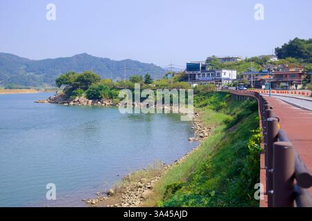 Gwangyang, Corea del Sud - 3 ottobre 2021: Una vista panoramica della pista ciclabile del fiume Seomjin che si snoda lungo un villaggio sul fiume vicino alla fioritura delle prugne di Gwangyang Foto Stock