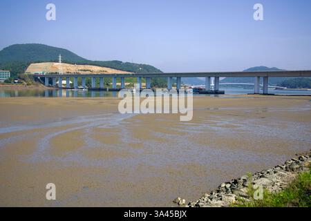 Gwangyang, Corea del Sud - 3 ottobre 2021: Il ponte Taein attraversa il fiume Seomjin, con le distese di marea esposte sotto di esso. Il moderno ponte collega Foto Stock