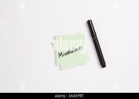 Nota cartacea con parole Mindfulness e pennarello nero su sfondo bianco minimale. Concetto di obiettivi e piani per il nuovo anno. Concetto di guarigione mentale Foto Stock