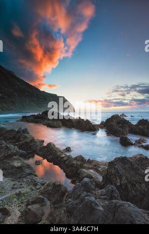 La piscina naturale dell'Oceano Atlantico, Porto Moniz a Madeira, Portogallo, con la costa rocciosa al tramonto con splendidi colori e vista panoramica Foto Stock