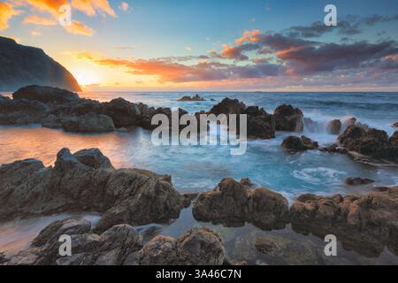 La piscina naturale dell'Oceano Atlantico, Porto Moniz a Madeira, Portogallo, con la costa rocciosa al tramonto con splendidi colori e vista panoramica Foto Stock