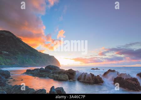 La piscina naturale dell'Oceano Atlantico, Porto Moniz a Madeira, Portogallo, con la costa rocciosa al tramonto con splendidi colori e vista panoramica Foto Stock