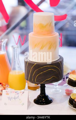 Una torta nuziale a tre piani dal design splendido presenta colori tenui e texture uniche esposte in occasione di un evento nuziale. Foto Stock