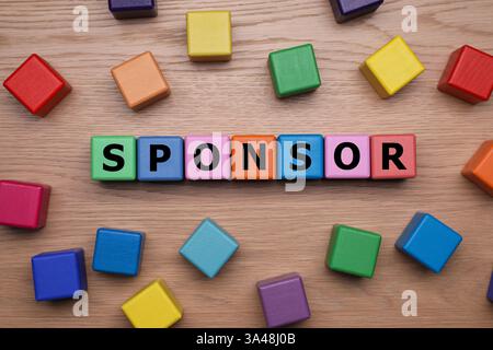 Word Sponsor composto da cubi colorati con lettere su un tavolo in legno, vista dall'alto Foto Stock