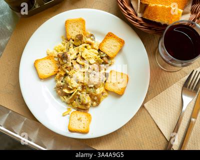 Omelette con funghi e aglio primaverile servita con crostini croccanti su piatto bianco. Foto Stock