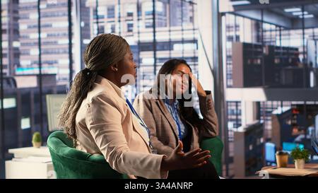 Donne d'affari frustrate che iniziano una discussione ed esprimono la loro irritazione, affrontano un fallimento aziendale e un esito negativo. Stressati associati arrabbiati che lottano in una riunione. Telecamera A.. Foto Stock