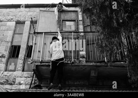 29 settembre 2014 - Gerusalemme, Israele - due giovani uomini iniziano a preparare una Sukkah in Yoel Street nel quartiere di Mea Shearim, uno dei più antichi quartieri ebraici di Gerusalemme, popolato dalla comunità ultra-ortodossa haredi. Sukkot, la Festa dei Tabernacoli, è una festa ebraica biblica ed è una delle tre feste di pellegrinaggio in cui gli Israeliti avrebbero fatto un pellegrinaggio al Tempio di Gerusalemme. (Immagine di credito: © Nir Alon/ZUMA Wire) Foto Stock