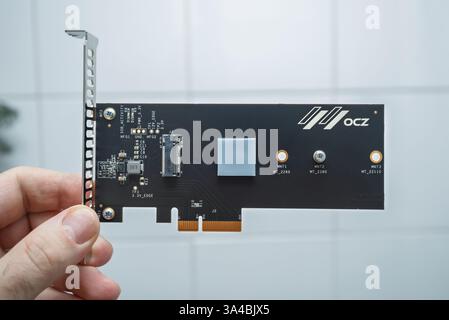 Parigi, Francia - 3 febbraio 2020: Vista ravvicinata di una mano che tiene in mano un circuito stampato con tecnologia OCZ, con componenti elettronici e connettori in primo piano Foto Stock