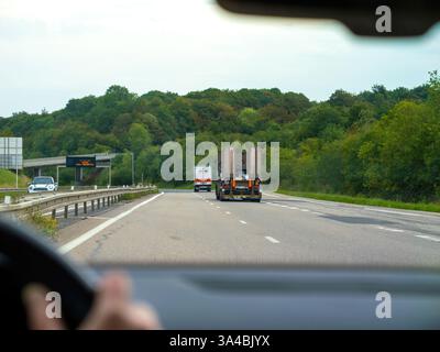 Nord, Francia - 24 agosto 2023: Vista da un'auto che guida su un'autostrada della Francia settentrionale, con un camion davanti e un fitto paesaggio forestale sullo sfondo. Foto Stock