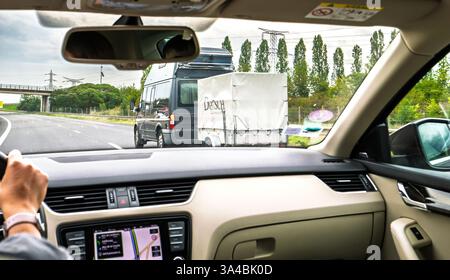 Nord, Francia - 24 agosto 2023: Vista dall'interno di un'auto che mostra una donna che guida su un'autostrada con navigazione GPS attiva sul cruscotto, che tiene traccia del ro Foto Stock