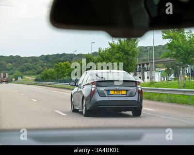 Nord, Francia - 24 agosto 2023: Vista da dietro un'auto ibrida Toyota che guida su un'autostrada in un ambiente verde lussureggiante, che illustra un tra moderno ed ecologico Foto Stock