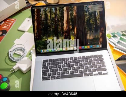 Parigi, Francia - 13 marzo 2025: Un laptop MacBook Air M4 appena non confezionato è completamente configurato e acceso, con una carta da parati boschiva, circondato da un accesso Foto Stock