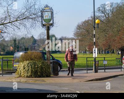 Cartello del villaggio di Theydon Bois, Essex, Regno Unito, con pedonale e verde villaggio sullo sfondo Foto Stock