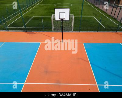 Vista aerea dei campi da pallacanestro e calcio all'aperto con colori blu, arancione e verde vivaci. L'impianto sportivo è vuoto, con contrassegni chiari e. Foto Stock