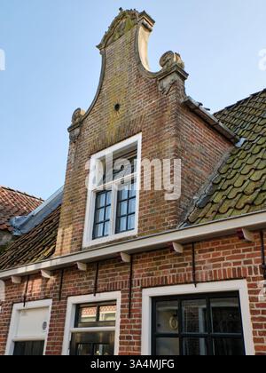 10 marzo 2025 - Grou-Paesi Bassi: Storica casa olandese in mattoni con una facciata a gradini, finestre tradizionali e tegole intemprate sotto un trasparente Foto Stock