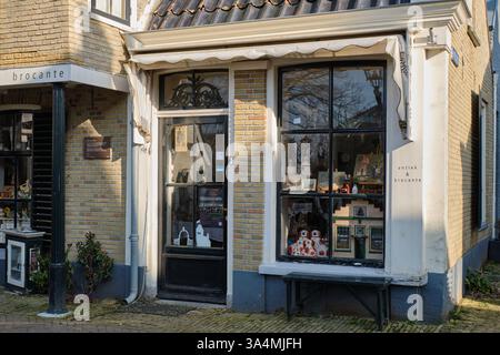 10 marzo 2025 - Grou-Paesi Bassi: Affascinante negozio di antiquariato e brocante con una classica facciata in mattoni, una grande vetrina e dettagli decorativi su una S. Foto Stock