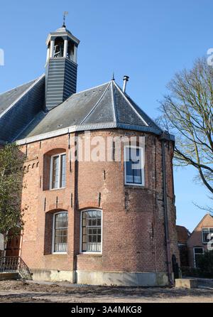 10 marzo 2025 - Grou-Paesi Bassi: Parte posteriore della storica chiesa di Grou, Frisia, con una struttura rotonda in mattoni, finestre ad arco, un roo di ardesia Foto Stock