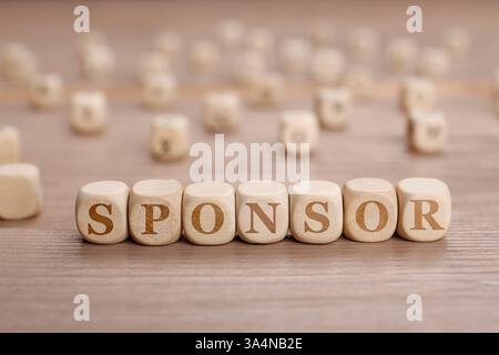 Word Sponsor composto da cubi con lettere su un tavolo di legno Foto Stock