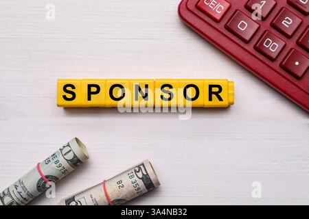 Word Sponsor realizzato in cubi gialli con lettere, banconote in dollari e calcolatrice su tavolo in legno, vista dall'alto Foto Stock