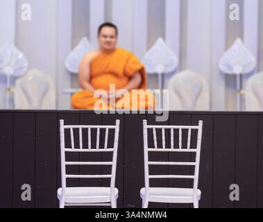 Un paio di sedie bianche sotto un podio con monaco buddista pronto per un rituale nuziale Foto Stock