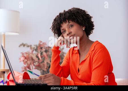 Donna afroamericana premurosa che studia con notebook e notebook a casa Foto Stock