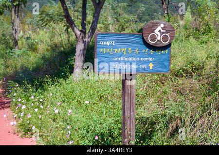 Contea di Damyang, Corea del Sud - 23 settembre 2020: Un cartello in legno lungo la pista ciclabile di Yeongsangang punta i ciclisti verso il certificato della diga di Damyang Foto Stock