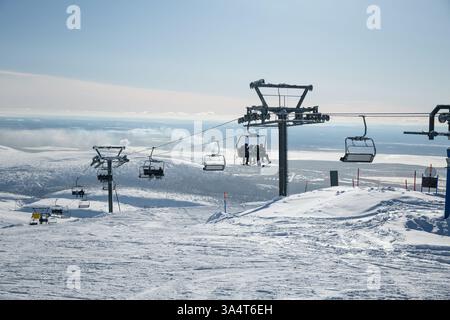 Sciatori e snowboarder fanno un giro in seggiovia sullo sfondo di un paesaggio montano invernale Foto Stock