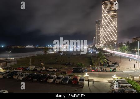 Colombo Sri Lanka - 1 settembre 2024; scena notturna su Galle Face Green, auto parcheggiate e moderno e alto edificio commerciale fino alla struttura del porto distante Foto Stock