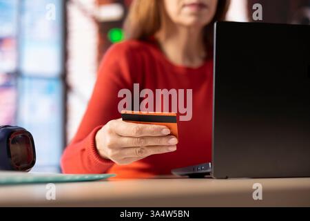 Una persona matura inserisce i numeri di carta online per richiedere un mutuo ipotecario o un prestito, compilando moduli e documenti sul sito web del suo ufficio di casa. Un'adulta sicura che conferma il suo reddito con la banca. Foto Stock
