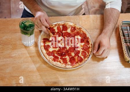 Vista ravvicinata dell'uomo che sta mangiando pizza, seduto. Foto Stock