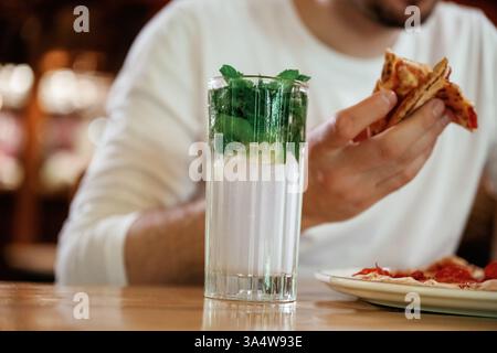 Vista ravvicinata dell'uomo che sta mangiando pizza, seduto. Foto Stock