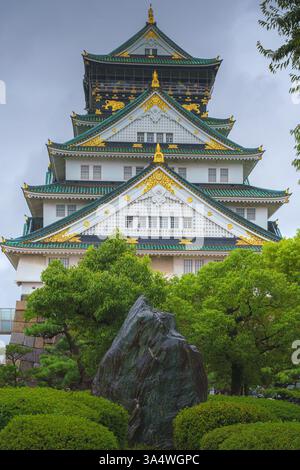Osaka, Giappone - 22 settembre 2024, vista panoramica del castello di Osaka tra gli alberi, da dietro le mura della fortezza e il fogliame degli alberi, in una giornata di pioggia Foto Stock