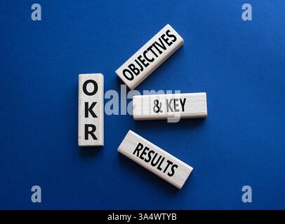 Obiettivi OKR e simbolo dei risultati chiave. Blocchi di legno con parole obiettivi OKR e risultati chiave. Splendido sfondo blu intenso. Business e OKR conce Foto Stock