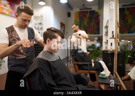 Parrucchiere taglio capelli di giovane modella femminile in salone Foto Stock