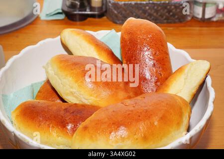 Torte fatte in casa appena sfornate con una crosta marrone dorata in una ciotola bianca su un rustico tavolo di legno. la consistenza calda e friabile e il ricco aroma evocano un senso di comfort a casa e di cottura tradizionale. concetto di cottura casalinga, cucina tradizionale, cibo confortevole. Foto Stock