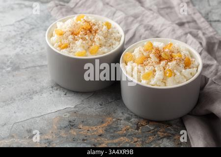 Delicato budino di riso dolce con cannella e uvetta dorata primo piano in ramekin sul tavolo. Orizzontale Foto Stock
