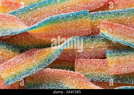 Colorato nastro di zucchero caramelle. Caramelle gelatinose in cospargetti di zucchero. Vista dall'alto. Striscia di caramelle in gelatina Rainbow Sour. Vista dall'alto. Sfondo astratto. Foto Stock