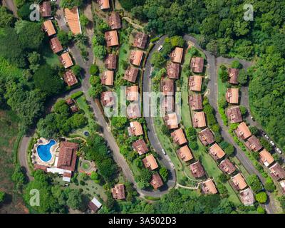 Residence tropicale con case sul tetto rosso e vista sulla strada e sulla piscina sopra il tetto dei droni Foto Stock