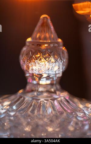 Piatto di caramelle in cristallo illuminato dalla luce del sole. Vaso sfaccettato con coperchio per riporre gioielli e caramelle Foto Stock
