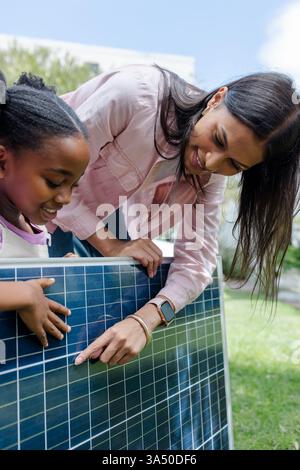 Esplorando la tecnologia dei pannelli solari, madre e figlio imparano a conoscere le energie rinnovabili all'aperto Foto Stock