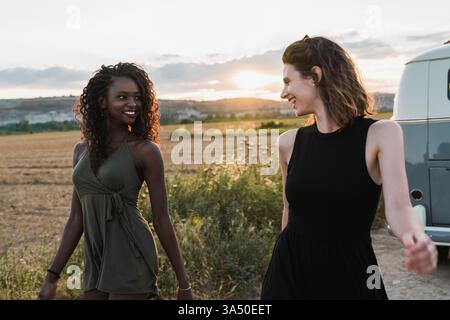 Le donne sorridenti nere e ispaniche si uniscono in campagna, condividendo un momento di amicizia. Un tema di viaggio e amicizia adatto per lo stile di vita all'aperto, la natura e i contenuti di avventura. Foto Stock