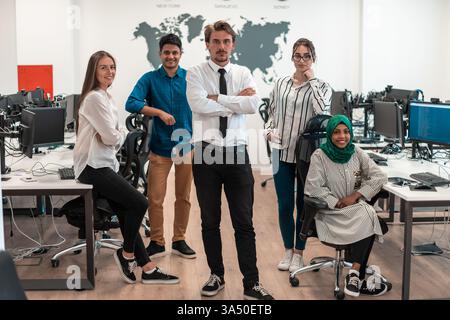 Ritratto di un giovane ed eccitato team aziendale multietnico composto da sviluppatori di software in piedi e che guarda la fotocamera nel moderno ufficio di startup. Alta qualità Foto Stock