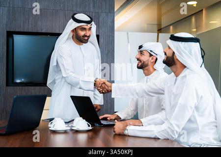 Gruppo di uomini d'affari arabi aziendali che si incontrano in ufficio - uomini d'affari del Medio Oriente che indossano kandora degli emirati che lavorano in una sala riunioni, Dubai Foto Stock